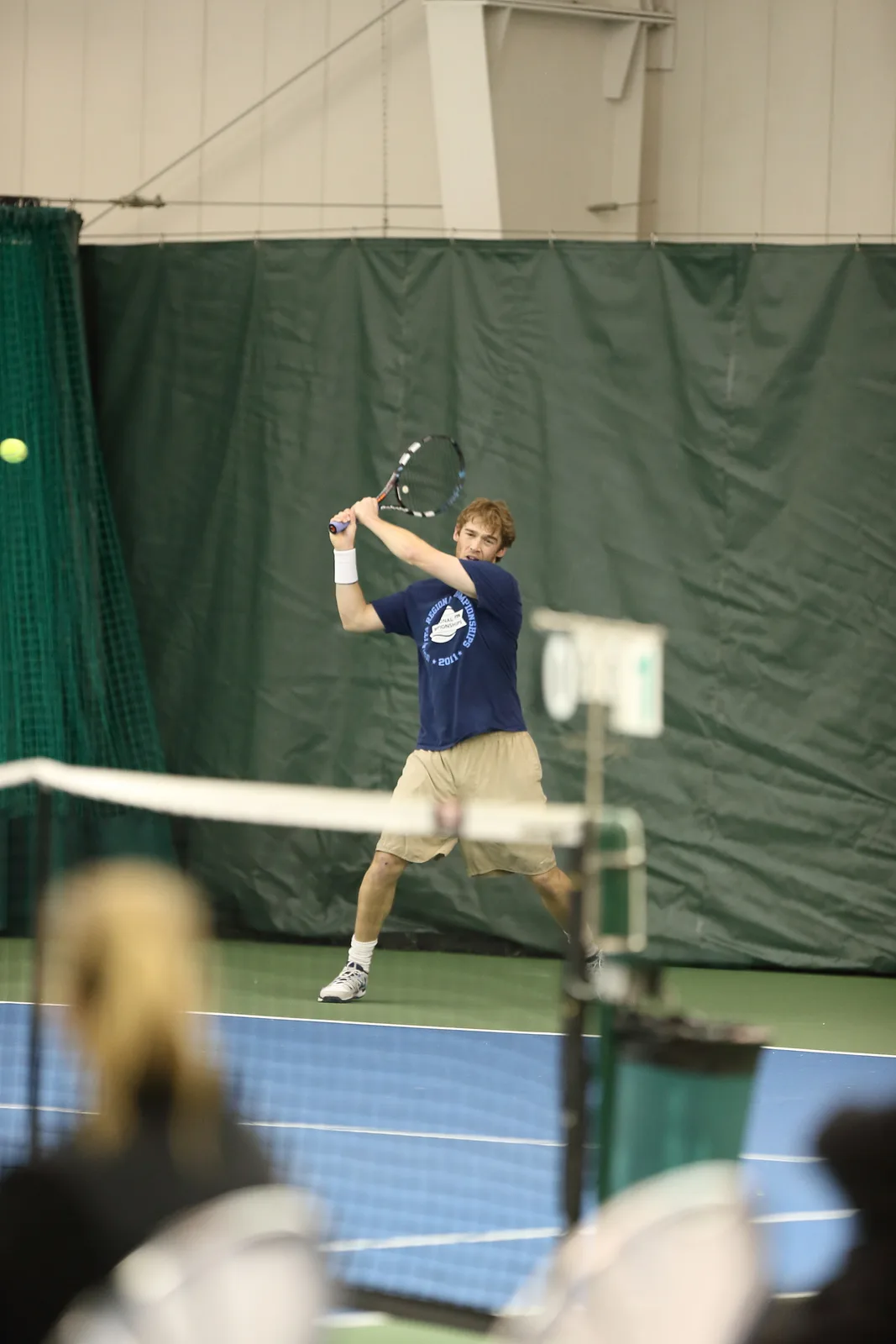 Sam Sweeney reaching for a forehand on an indoor court