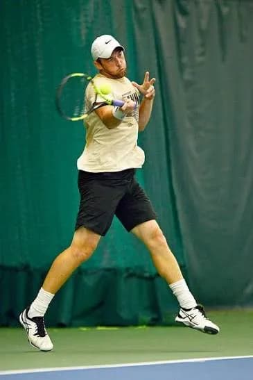 Sam Sweeney hitting a forehand on an indoor court