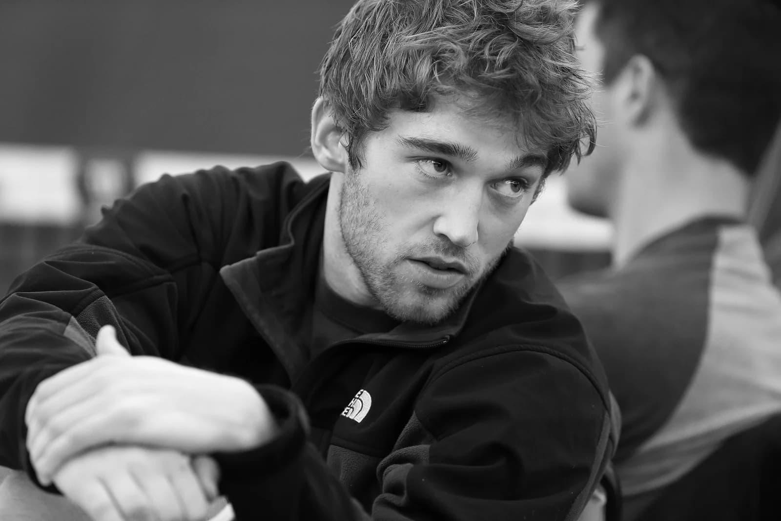 Black-and-white close-up of Sam Sweeney in a North Face fleece, mid-conversation